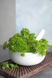 Mortar with fresh green parsley on table