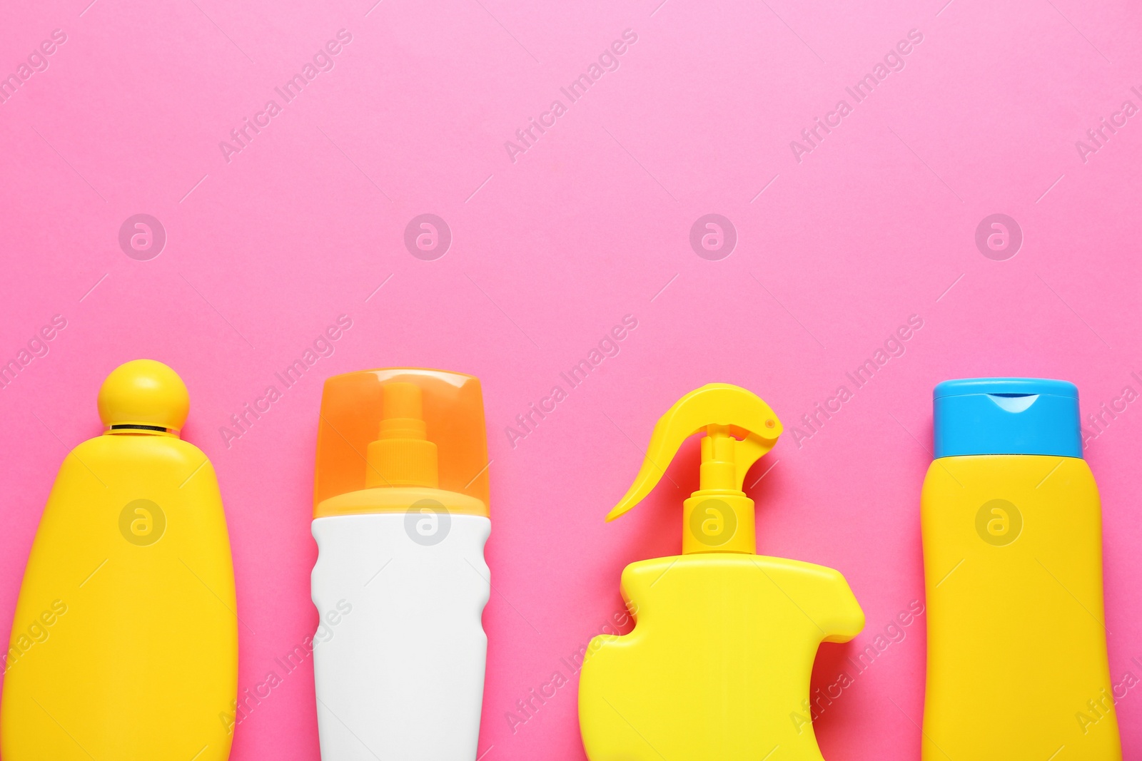 Photo of Suntan products on pink background, flat lay. Space for text