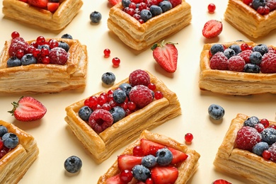Photo of Fresh delicious puff pastry with sweet berries on beige background