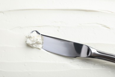 Photo of Tasty cream cheese and knife, closeup view