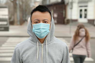 Photo of Asian man wearing medical mask on city street. Virus outbreak