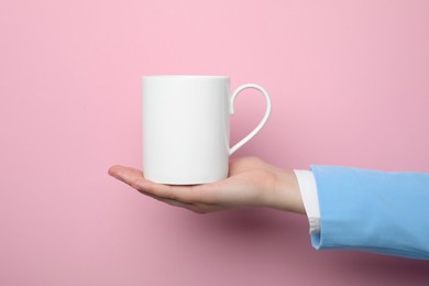 Photo of Woman holding white mug on pink background, closeup