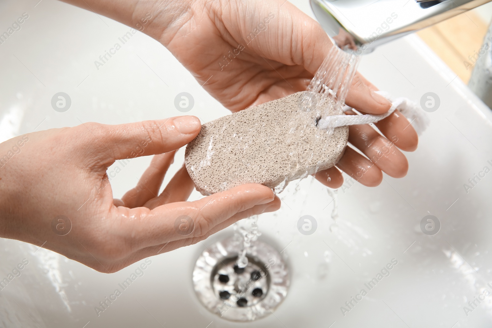Photo of Woman pouring water onto pumice stone in bathroom, above view