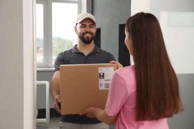 Photo of Woman receiving parcel from courier at home