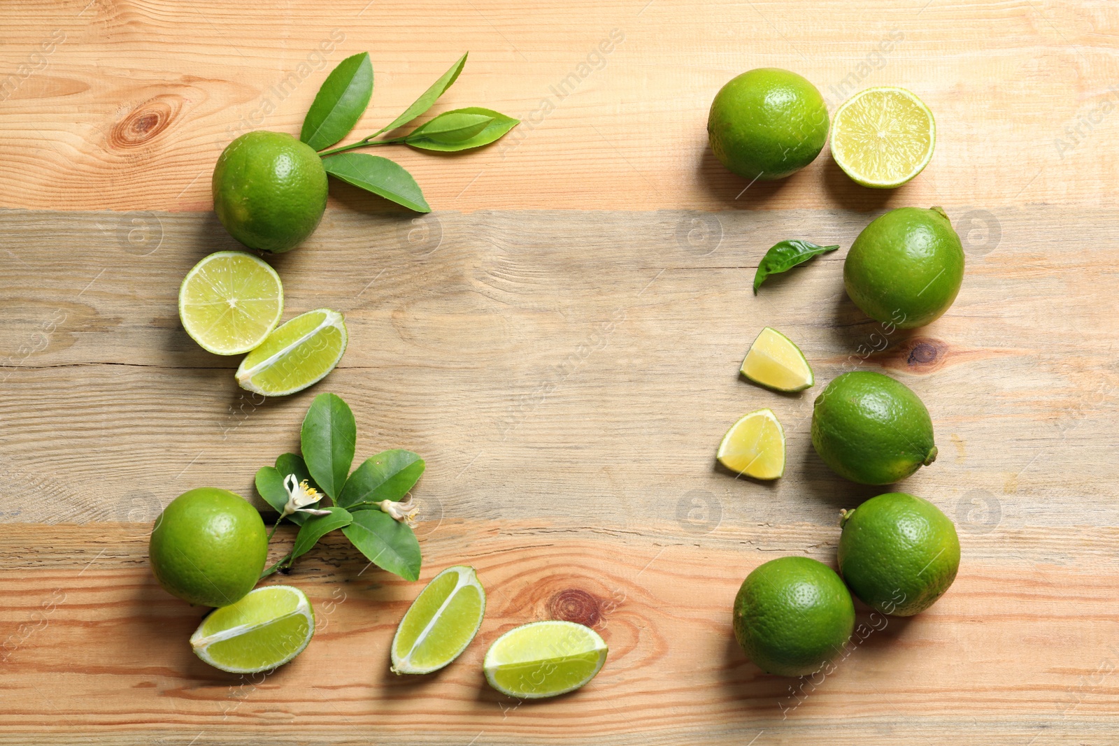 Photo of Frame of fresh ripe limes on wooden background, top view