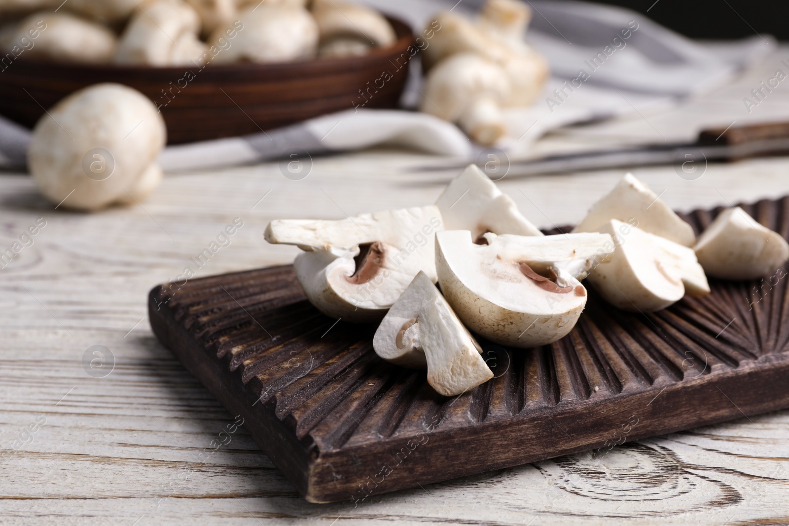 Photo of Cutting board with fresh raw mushrooms on wooden table