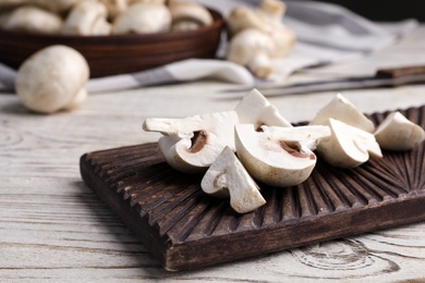 Cutting board with fresh raw mushrooms on wooden table