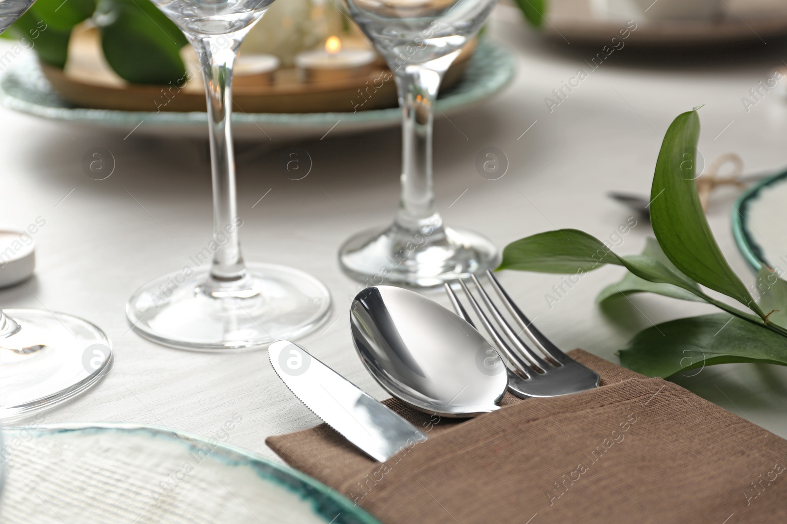 Photo of Elegant cutlery with green plant on table, closeup. Festive setting