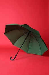 Photo of Stylish open green umbrella on red background
