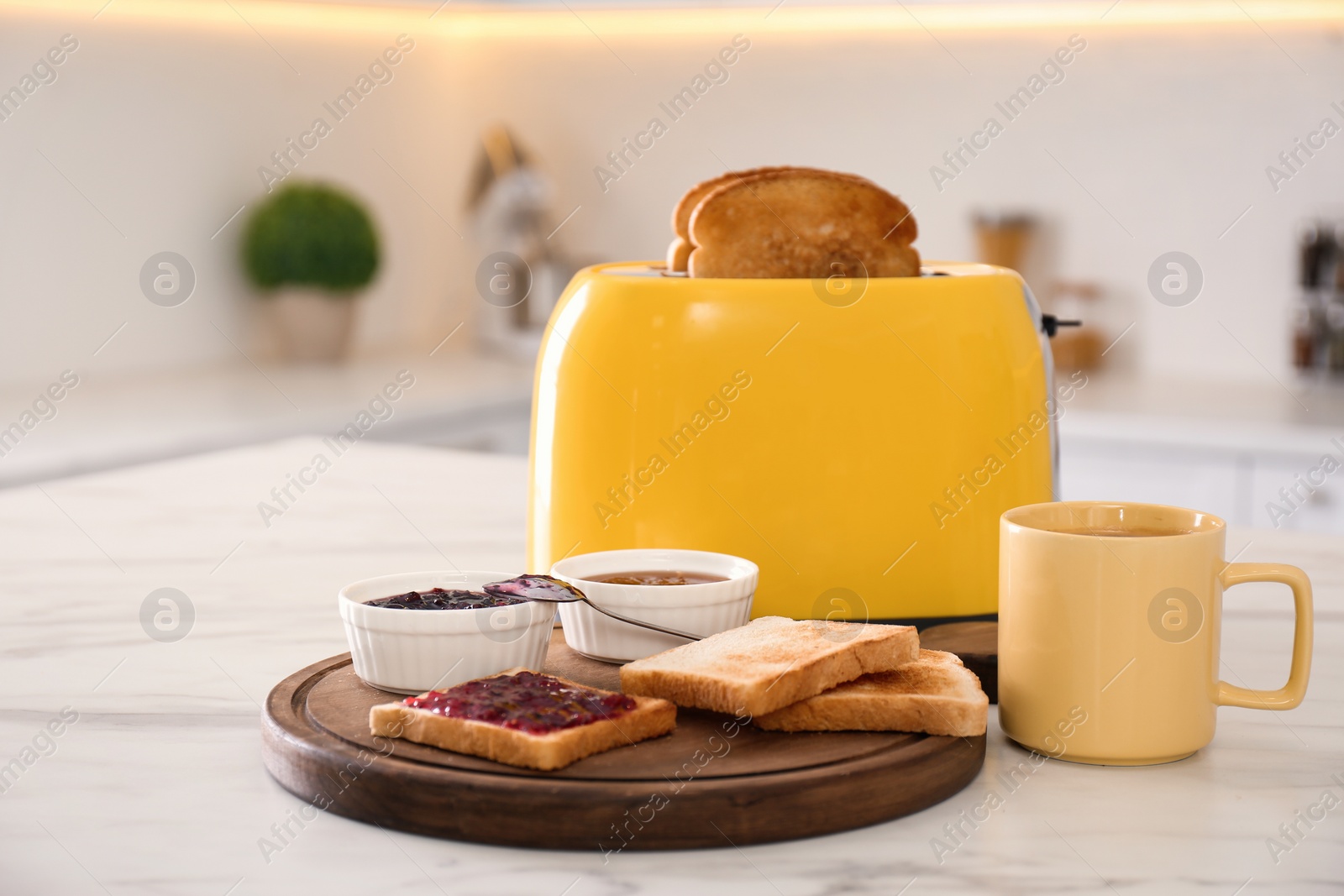 Photo of Modern toaster and tasty breakfast on white marble table in kitchen