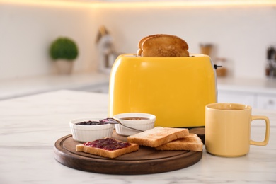 Modern toaster and tasty breakfast on white marble table in kitchen