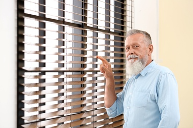 Photo of Portrait of handsome mature man near window with blinds