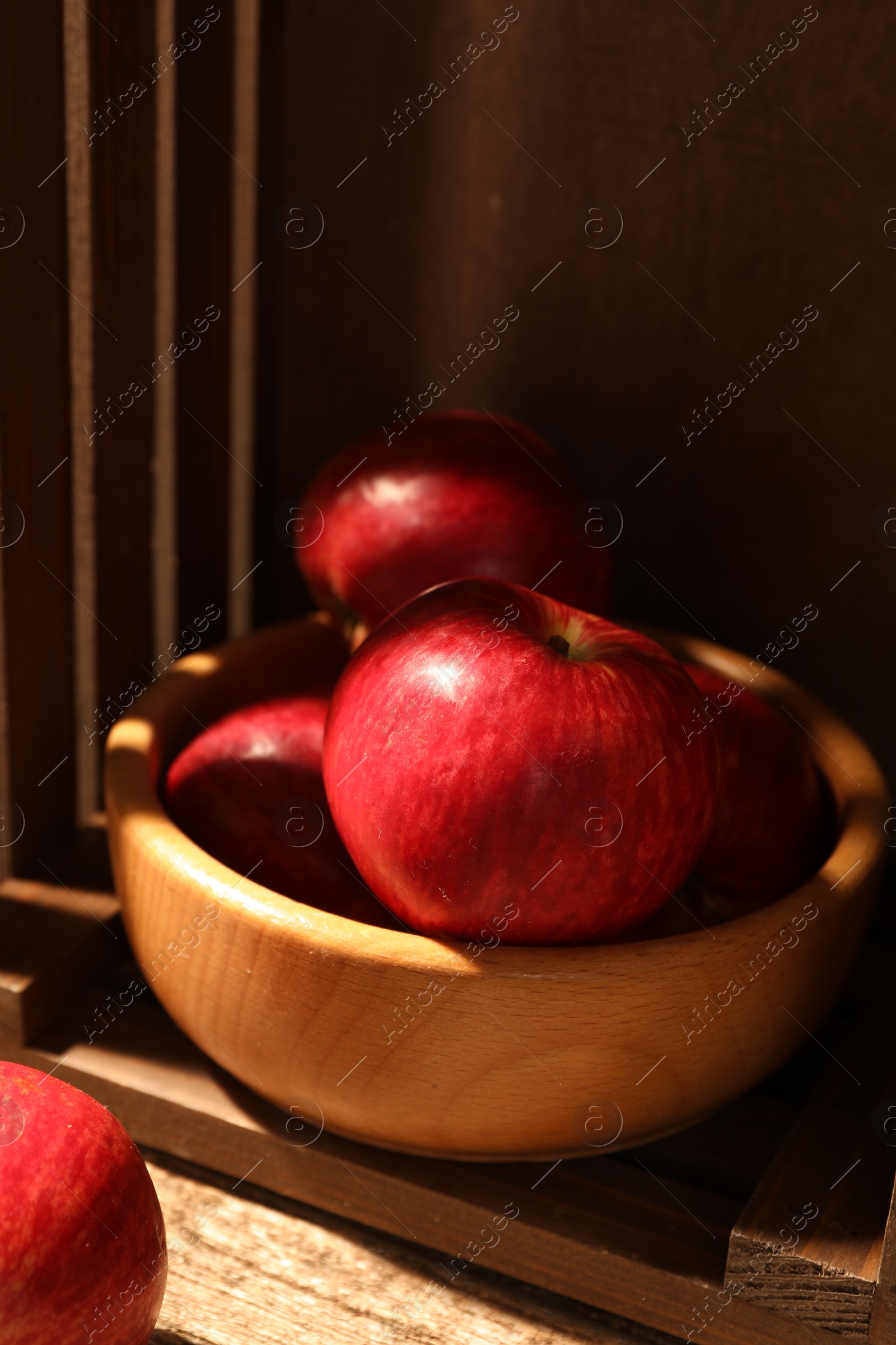 Photo of Fresh red apples in bowl on wooden table, closeup