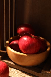 Photo of Fresh red apples in bowl on wooden table, closeup