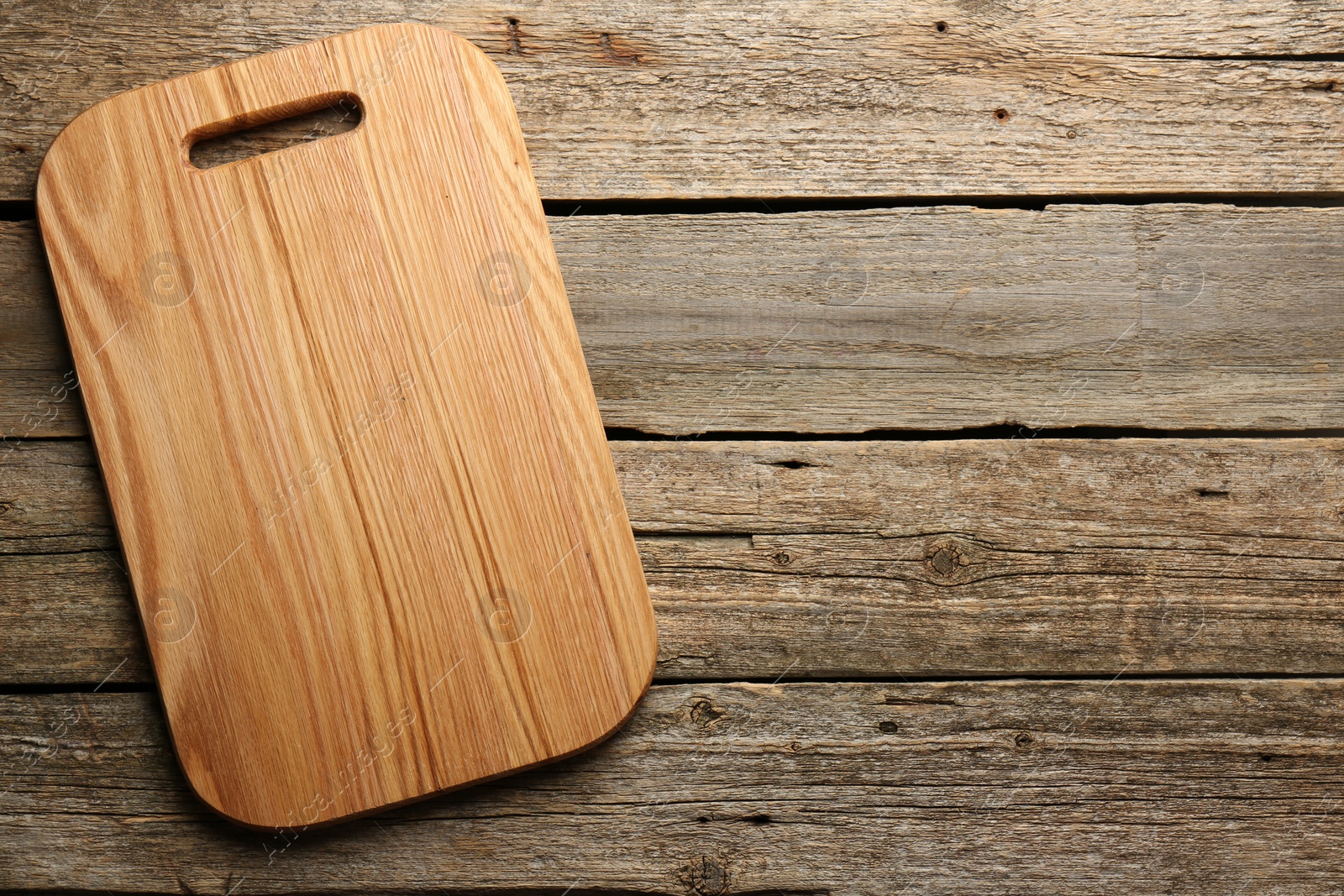 Photo of One new cutting board on old wooden table, top view. Space for text