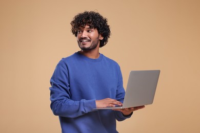 Photo of Smiling man with laptop on beige background