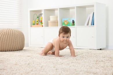 Cute baby boy crawling on carpet at home