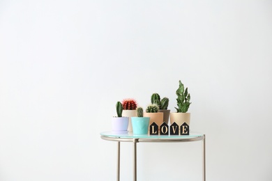 Photo of Beautiful cacti on table against light background