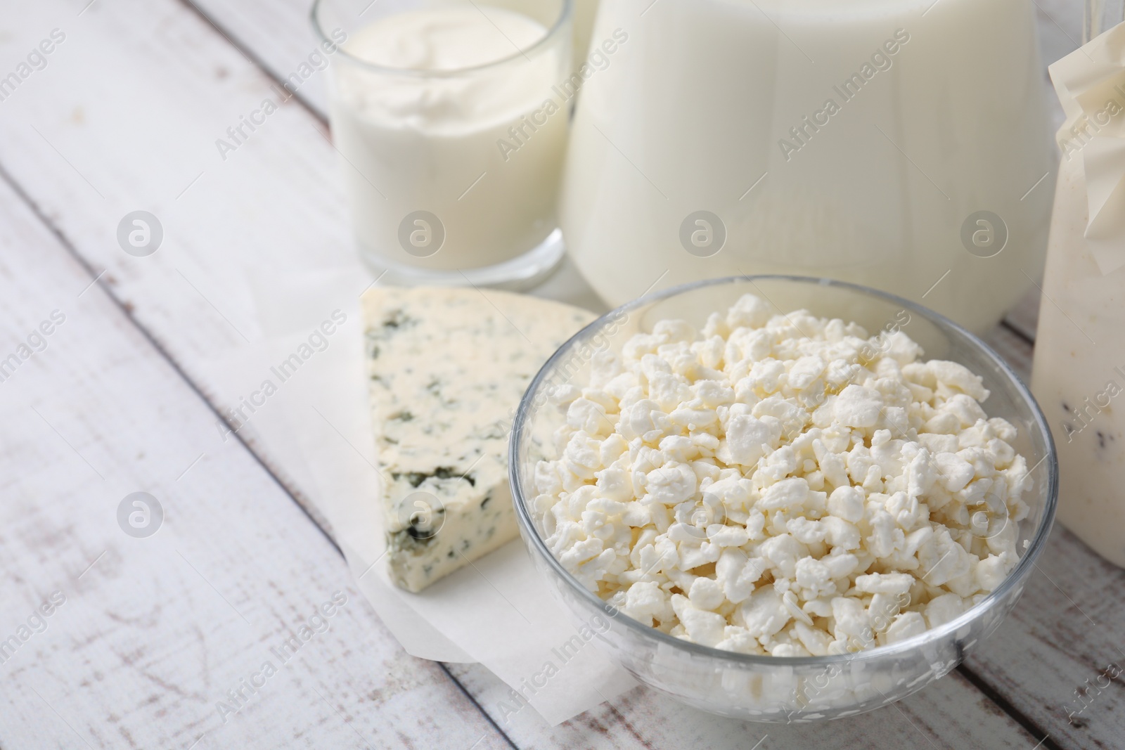 Photo of Different fresh dairy products on white wooden table. Space for text