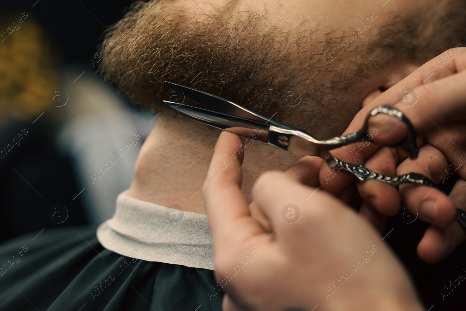 Photo of Professional hairdresser working with bearded client in barbershop, closeup