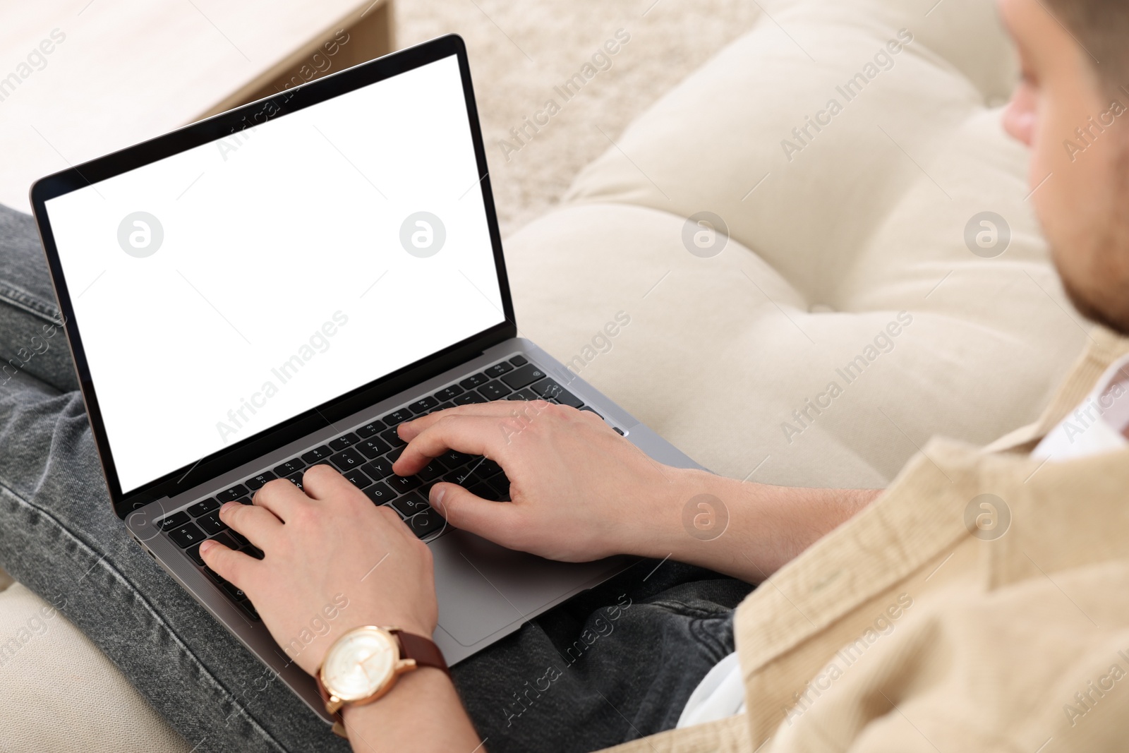 Photo of Man working with laptop on sofa indoors, closeup