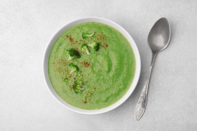 Photo of Delicious broccoli cream soup served on light table, flat lay