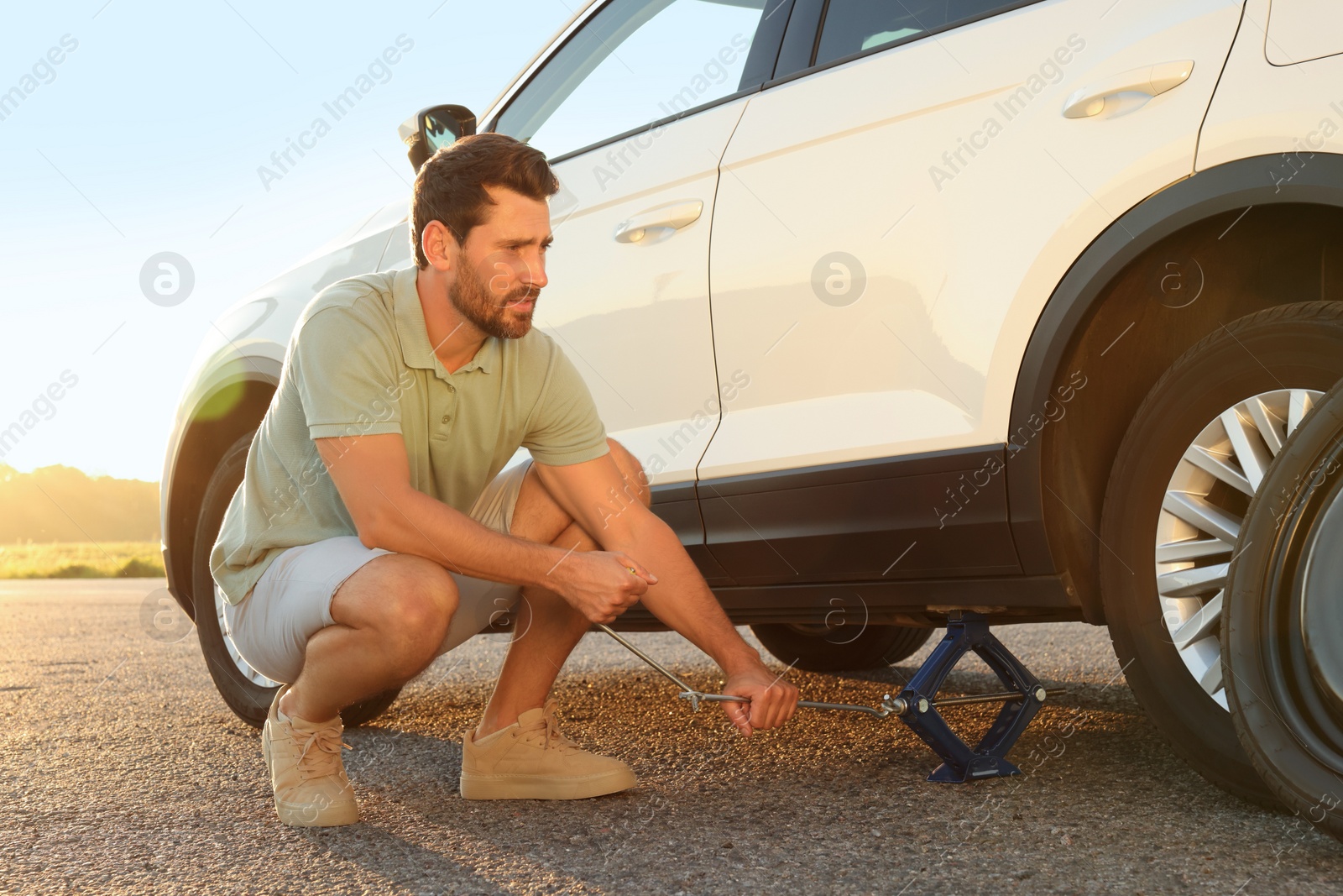 Photo of Man changing wheel of car on roadside