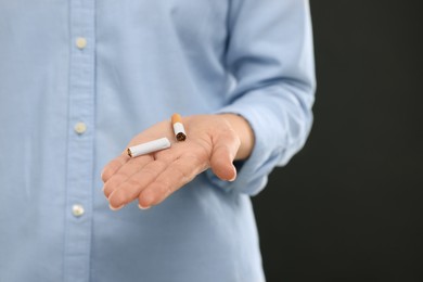 Photo of Stop smoking concept. Woman holding broken cigarette on black background, closeup. Space for text