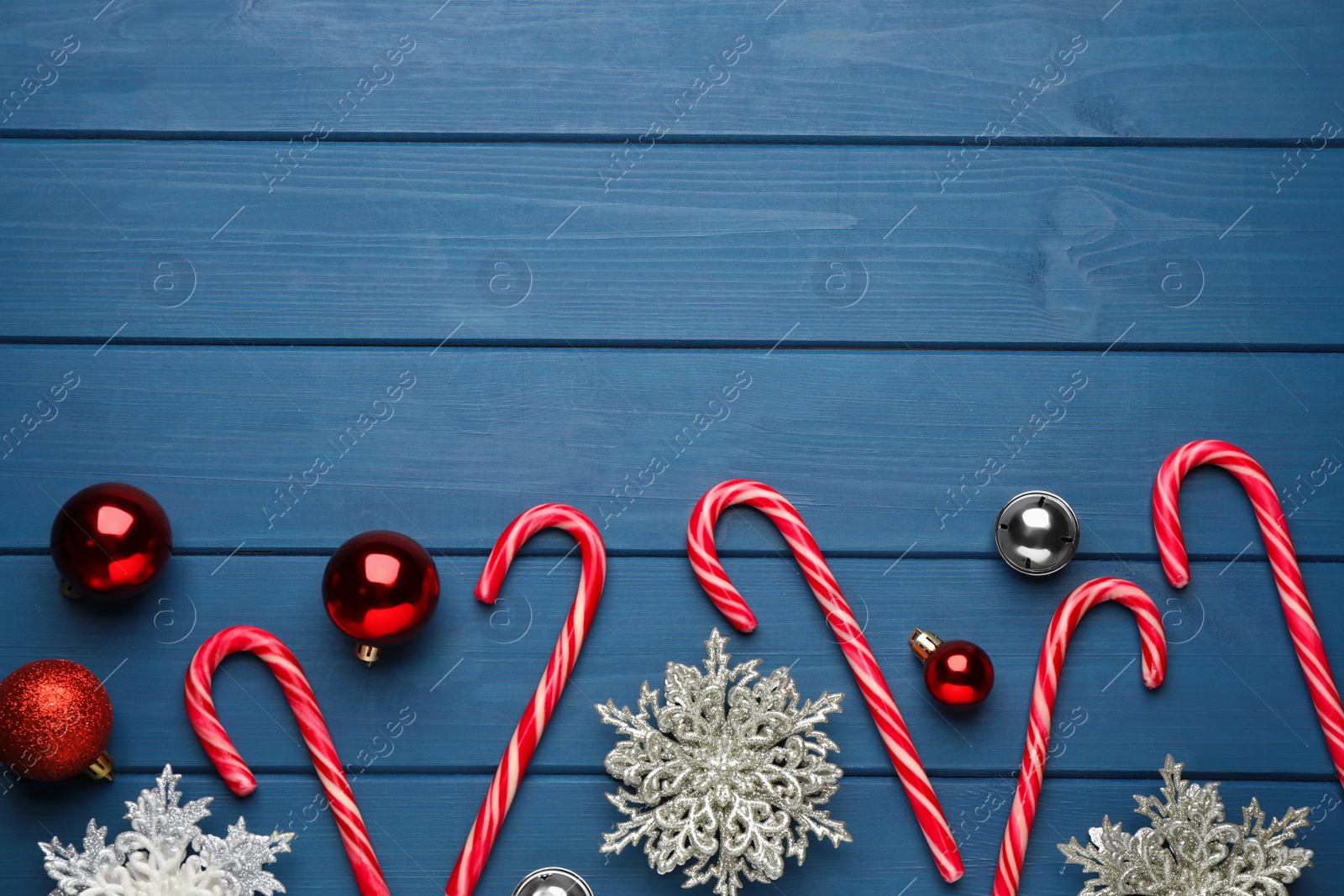 Photo of Tasty candy canes, Christmas balls and snowflakes on blue wooden table, flat lay. Space for text