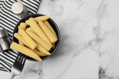 Photo of Bowl of pickled baby corn, pepper shaker and fork on white marble table, flat lay. Space for text