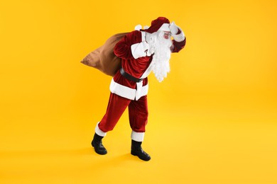 Photo of Full length portrait of Santa Claus with sack on yellow background