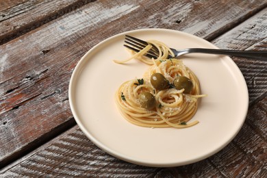 Photo of Heart made of tasty spaghetti, fork, olives and cheese on wooden table
