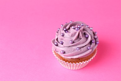 Photo of Delicious cupcake with bright cream and sprinkles on pink background