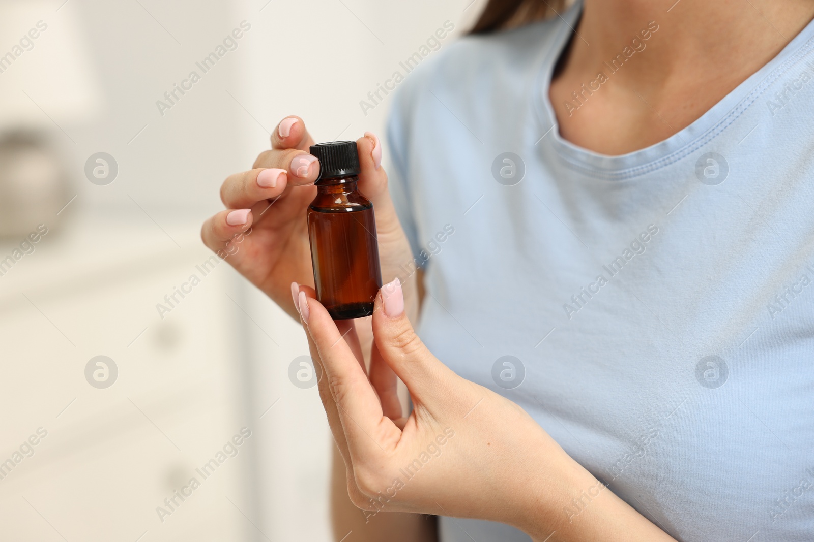 Photo of Aromatherapy. Woman with bottle of essential oil on light background, closeup