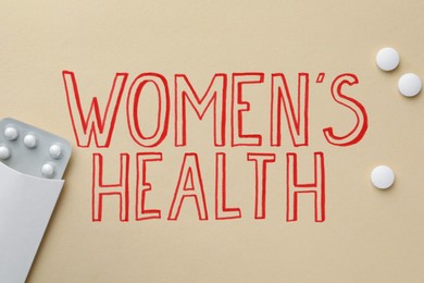 Photo of Words Women's Health and pills on beige background, flat lay