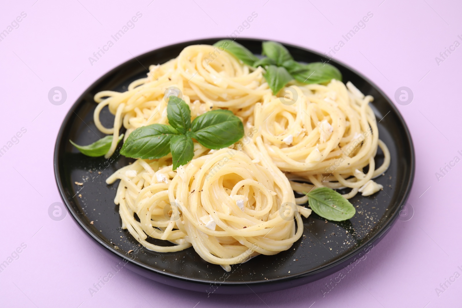 Photo of Delicious pasta with brie cheese and basil leaves on violet background, closeup