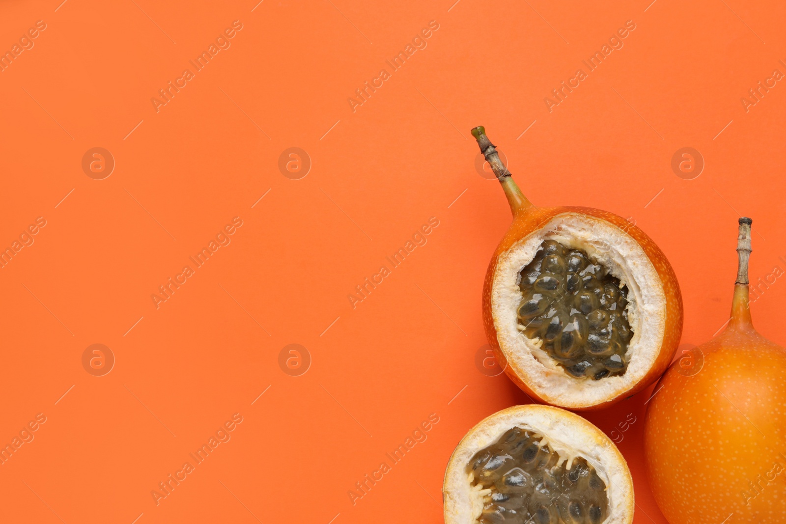 Photo of Delicious ripe granadillas on orange background, flat lay. Space for text