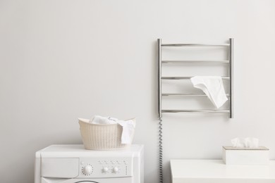 Photo of Heated towel rail with underwear on white wall in bathroom, space for text