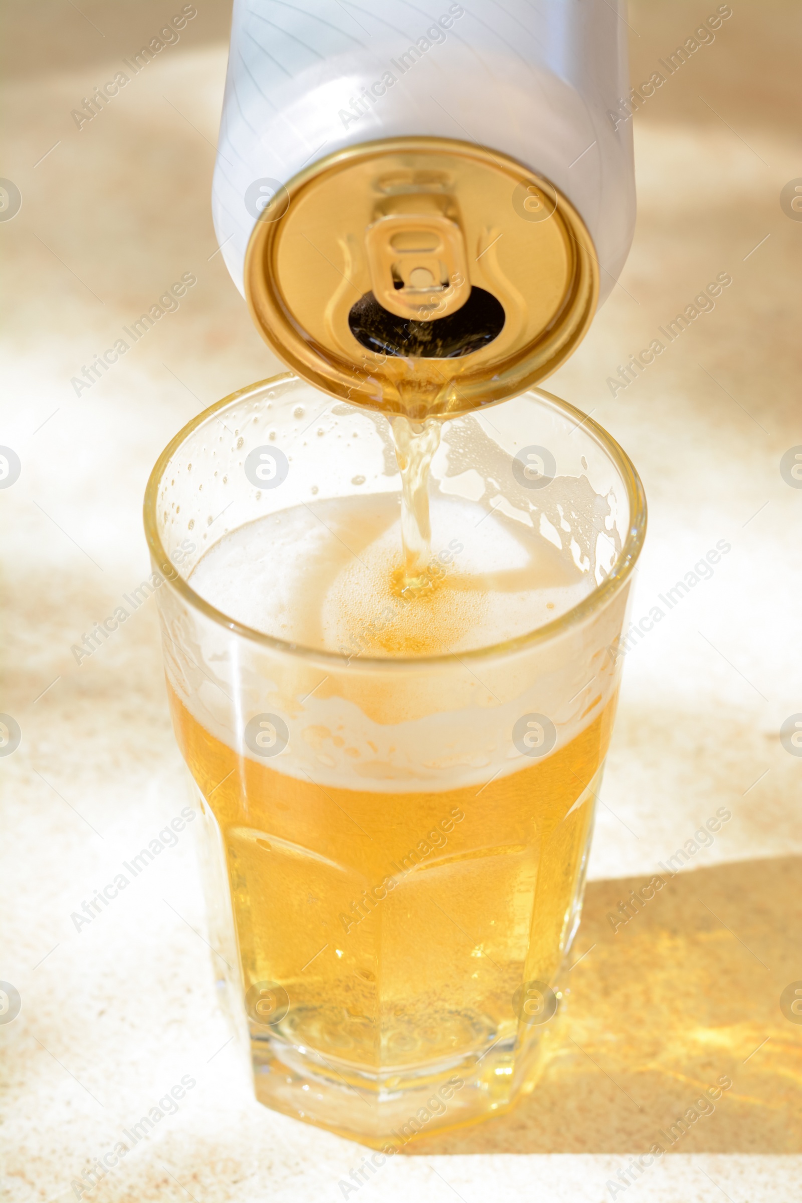 Photo of Pouring beer from can into glass on table, closeup