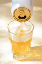 Photo of Pouring beer from can into glass on table, closeup