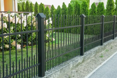 Photo of Beautiful black iron fence near pathway outdoors