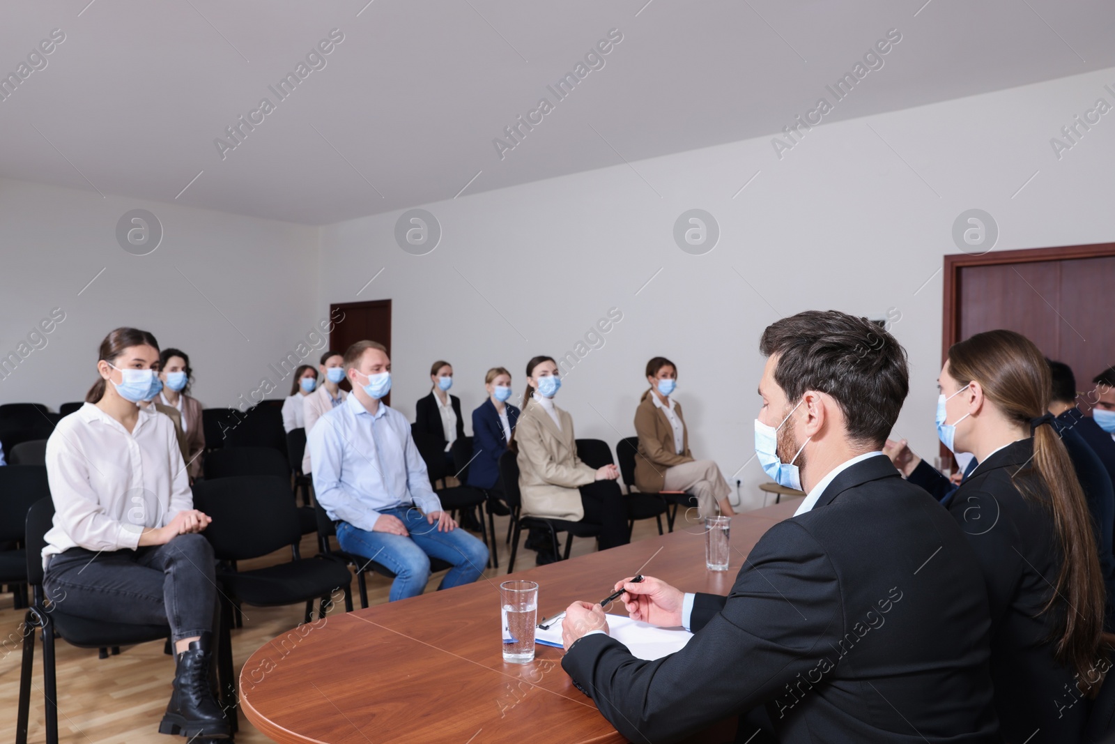 Photo of Business conference. People with protective masks listening to speaker report