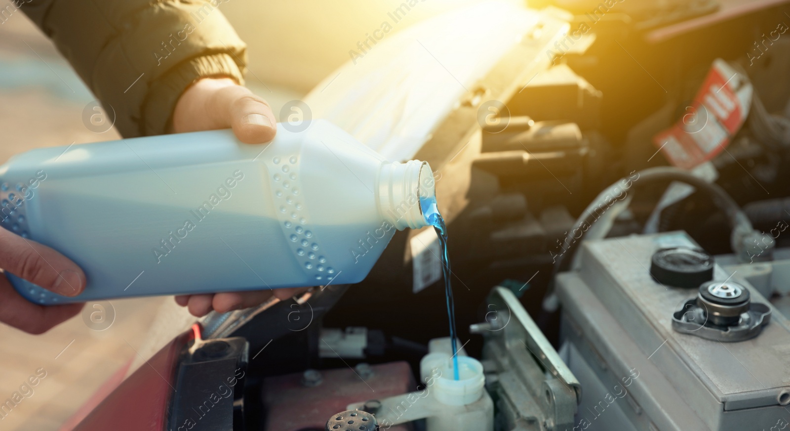 Image of Man filling car radiator with antifreeze outdoors, closeup