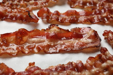 Photo of Slices of tasty fried bacon on white table, closeup