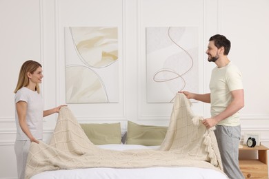 Photo of Couple changing bed linens at home. Domestic chores