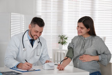 Doctor measuring blood pressure of pregnant woman in clinic