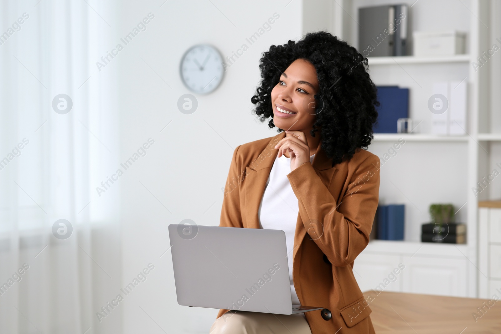 Photo of Smiling young businesswoman using laptop in modern office