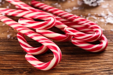 Photo of Sweet Christmas candy canes on wooden table, closeup