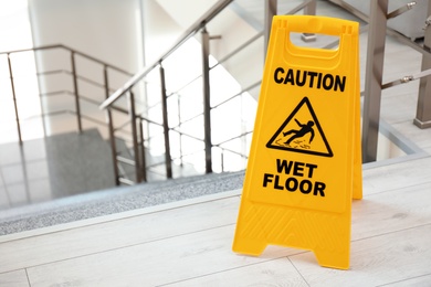 Photo of Safety sign with phrase Caution wet floor near stairs. Cleaning service