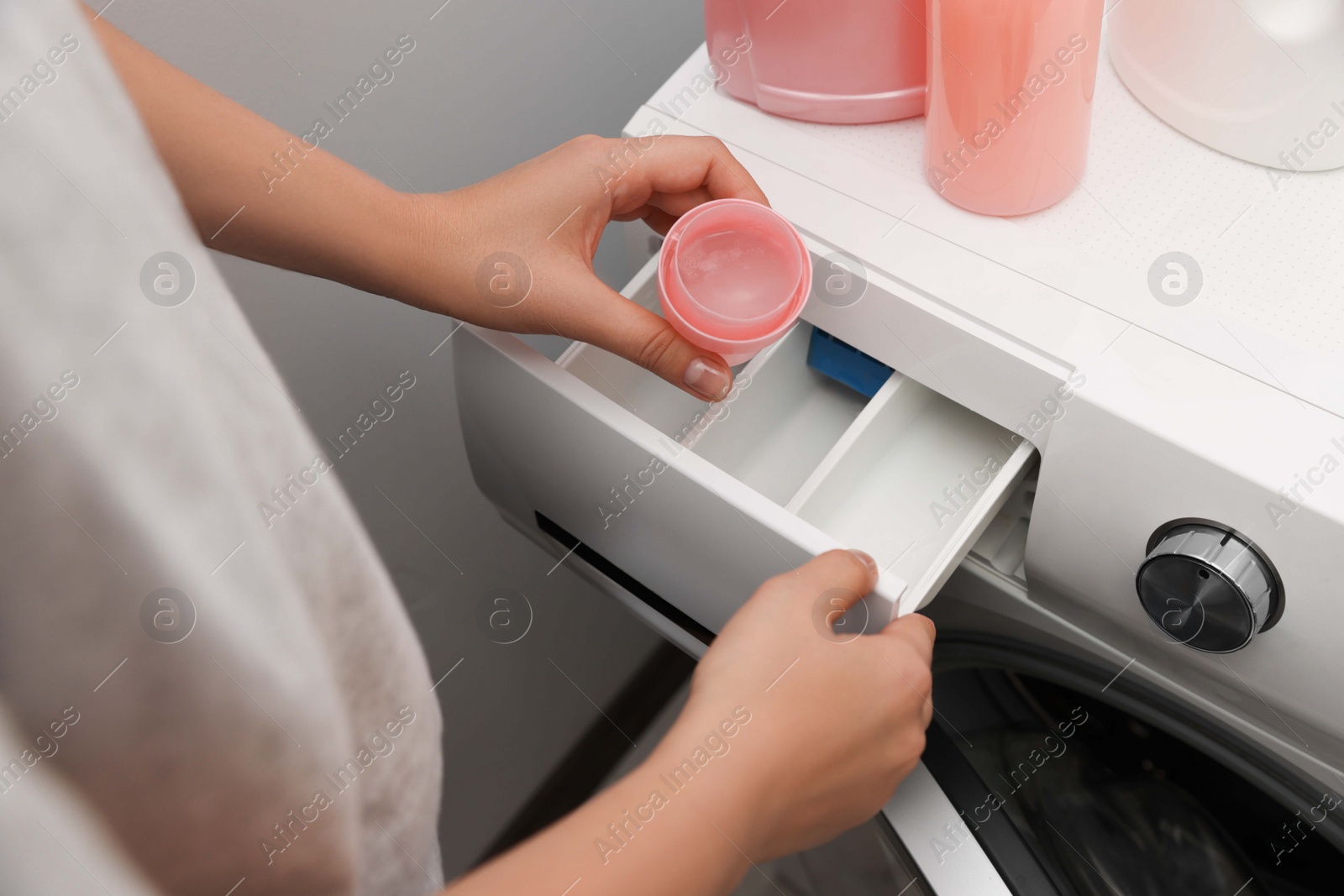 Photo of Woman pouring laundry detergent into drawer of washing machine, closeup